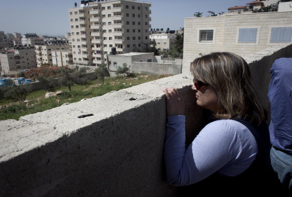 In this photo taken Wednesday, April 16, 2014, a female member of an Israeli and foreigner's group tour that is organized by IPCRI, an Israeli Palestinian group promoting co-existence, looks on toward a Palestinian neighbourhood while visiting the outskirts of the West Bank city of Ramallah. This bustling center of Palestinian life is just a 20-minute drive from Jerusalem, but for Israelis it might as well be on the other side of the world. (AP Photo/Nasser Nasser)