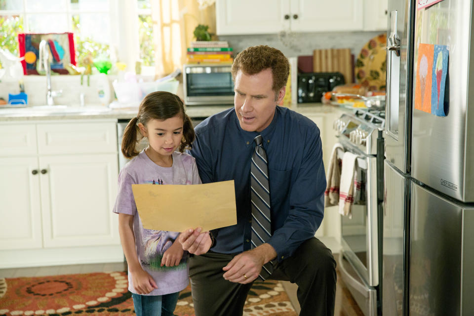 Will Ferrell kneeling to look at a piece of paper with Scarlett Estevez in the kitchen in the movie Daddy's Home