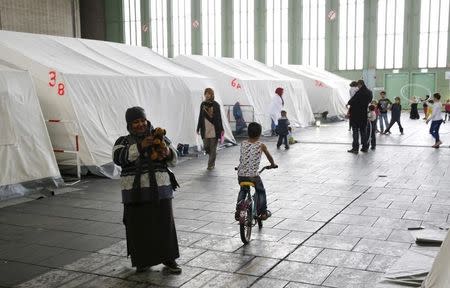 Migrants walk next to tents in a shelter for migrants inside a hangar of the former Tempelhof airport in Berlin, Germany, December 9, 2015. REUTERS/Fabrizio Bensch