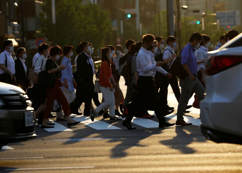 Office workers wearing protective face masks walk to head home at sunset amid the coronavirus disease (COVID-19) outbreak, in Tokyo