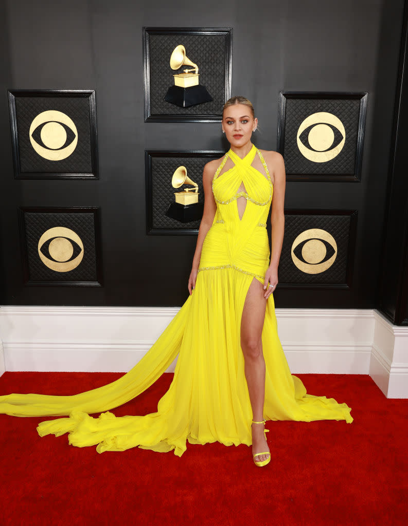 Kelsea Ballerini in draped acid yellow gown with flowing panels and halter neck.