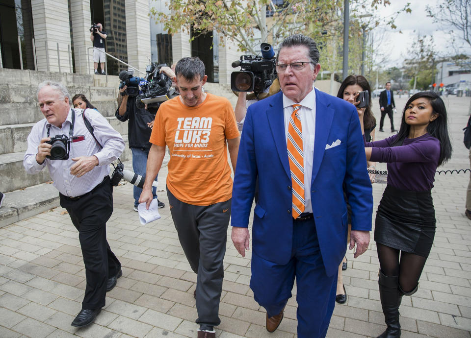 Texas men's tennis coach Michael Center, center left, walks with Defense lawyer Dan Cogdell, center right, away from the United States Federal Courthouse in Austin, Texas, Tuesday, March 12, 2019. Center is among a few people in the state charged in a scheme that involved wealthy parents bribing college coaches and others to gain admissions for their children at top schools, federal prosecutors said Tuesday. (Ricardo B. Brazziell