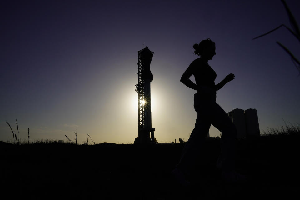 A woman runs past SpaceX's Starship, the world's biggest and most powerful rocket, standing ready for launch in Boca Chica, Texas, Sunday, April 16, 2023. The test launch is scheduled for Monday. (AP Photo/Eric Gay)