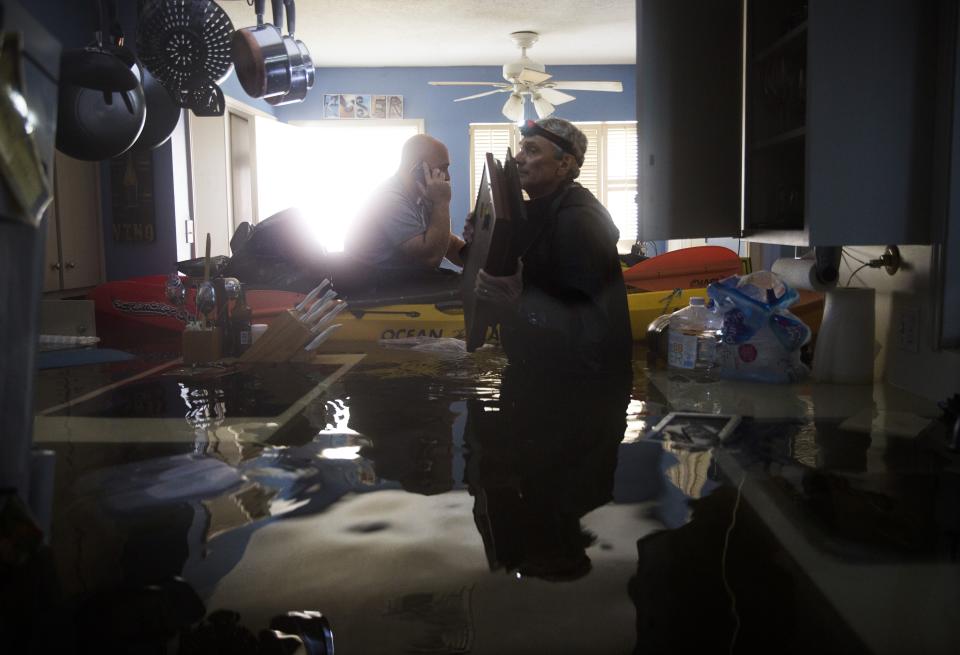 Larry Koser Jr., left, speaks on his phone as he and his father, Larry Koser Sr., look for important papers and heirlooms inside the family home, which flooded on Aug. 29. (Photo: Erich Schlegel/Getty Images)