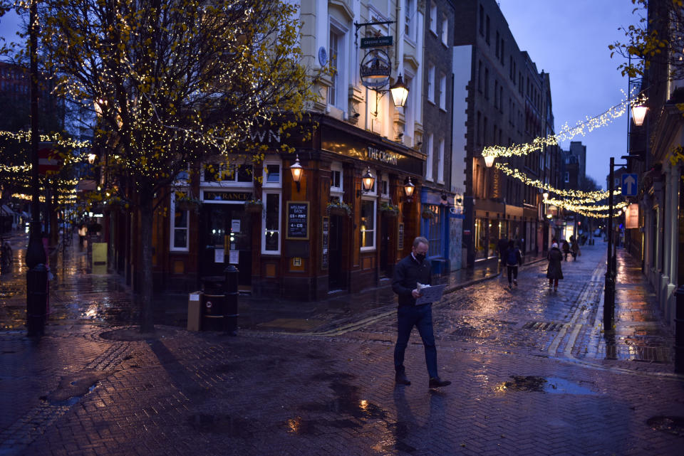 Un hombre con mascarilla camina frente a un pub cerrado en la zona Seven Dials de Covent Garden, en Londres, el miércoles 16 de diciembre de 2020. (AP Foto/Alberto Pezzali)