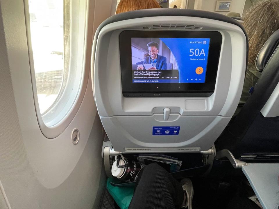 An airline seat with a water bottle in the storage compartment.