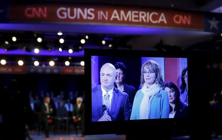 Former astronaut Mark Kelly and his wife, gun violence victim and former Arizona Rep. Gabrielle Giffords, are seen on a monitor as they listen to U.S. President Barack Obama speak during a live town hall event on reducing gun violence, hosted by CNNâ€™s Anderson Cooper, at George Mason University in Fairfax, Virginia January 7, 2016. REUTERS/Kevin Lamarque