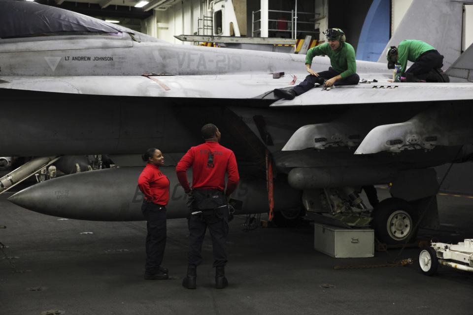 In this Tuesday, March 21, 2017 photograph, sailors work on an F-18 fighter jet on the USS George H.W. Bush as it travels through the Strait of Hormuz. The arrival of the nuclear-powered aircraft carrier to the Persian Gulf marks the first such deployment under new U.S. President Donald Trump. (AP Photo/Jon Gambrell)