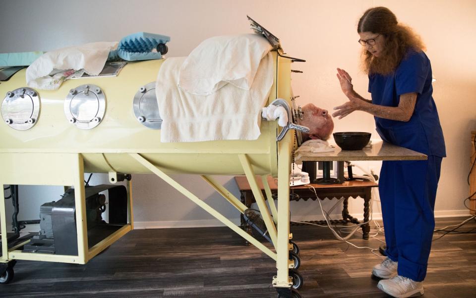 Caregiver and friend Kathy Gaines gives Paul Alexander a shave at his home in Texas, 2019