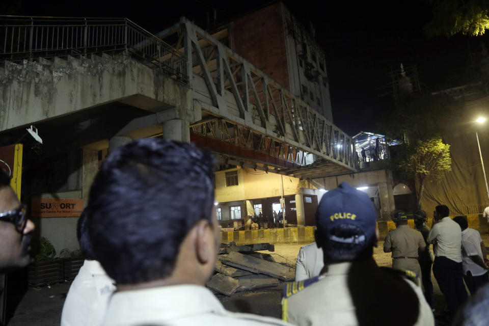Policemen and others gather near a pedestrian bridge that collapsed in Mumbai, India, Thursday, March 14, 2019. A pedestrian bridge connecting a train station with a road collapsed in Mumbai on Thursday, killing at least five people and injuring more than 30, police said. (AP Photo/Rajanish Kakade)