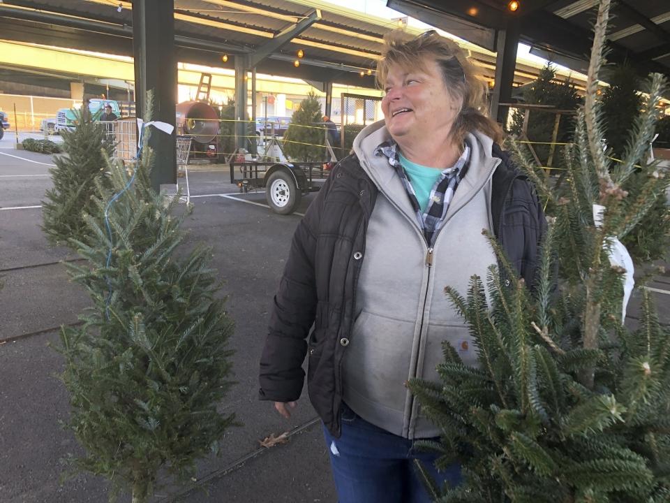 In this Saturday, Dec. 7, 2019 photo, Sandy Parsons speaks while tending to Christmas trees for sale on her lot at the Capitol Market in Charleston, W.Va. Parsons never received her order of 350 trees this year from a North Carolina farm, citing a short supply. Instead, she was sent a few much-smaller trees. Christmas trees are in tight supply again this year across the United States, depending upon location and seller, as the industry continues bouncing back from the Great Recession. (AP Photo/John Raby)