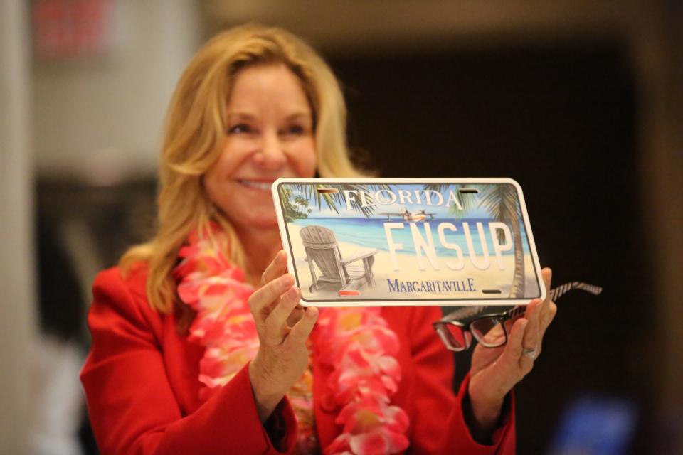 Rep. Linda Chaney, R- St. Petersburg, holds up a Jimmy Buffet specialty license plate prototype, Jan. 25, 2024.