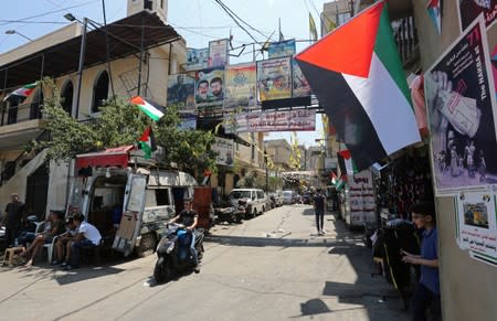 A boy rides on a motorbike as he drives past Palestinian flags at Burj al-Barajneh refugee camp in Beirut