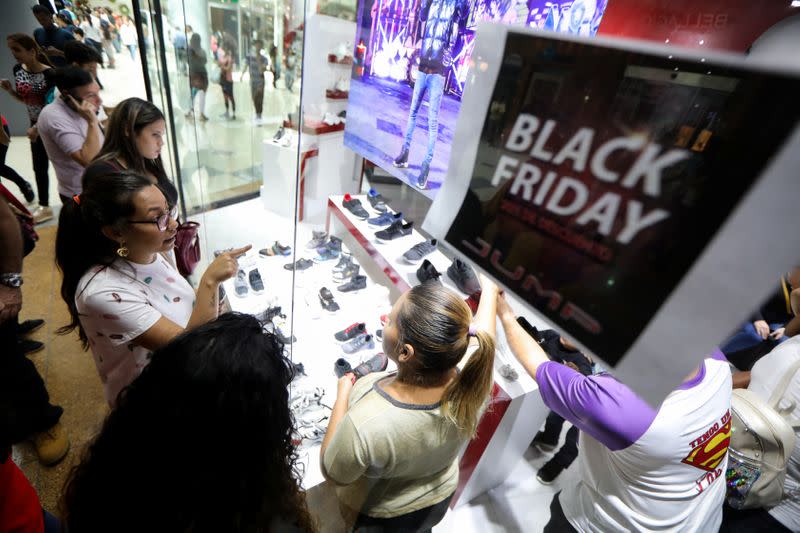 People watch products outside a store at a mall during the Black Friday sales in Caracas