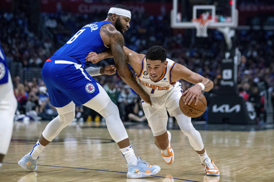 Phoenix Suns guard Devin Booker, right, drives past Los Angeles Clippers forward Marcus Morris Sr., during the first half of an NBA basketball game, Sunday, Oct. 23, 2022 in Los Angeles. (AP Photo/Alex Gallardo)