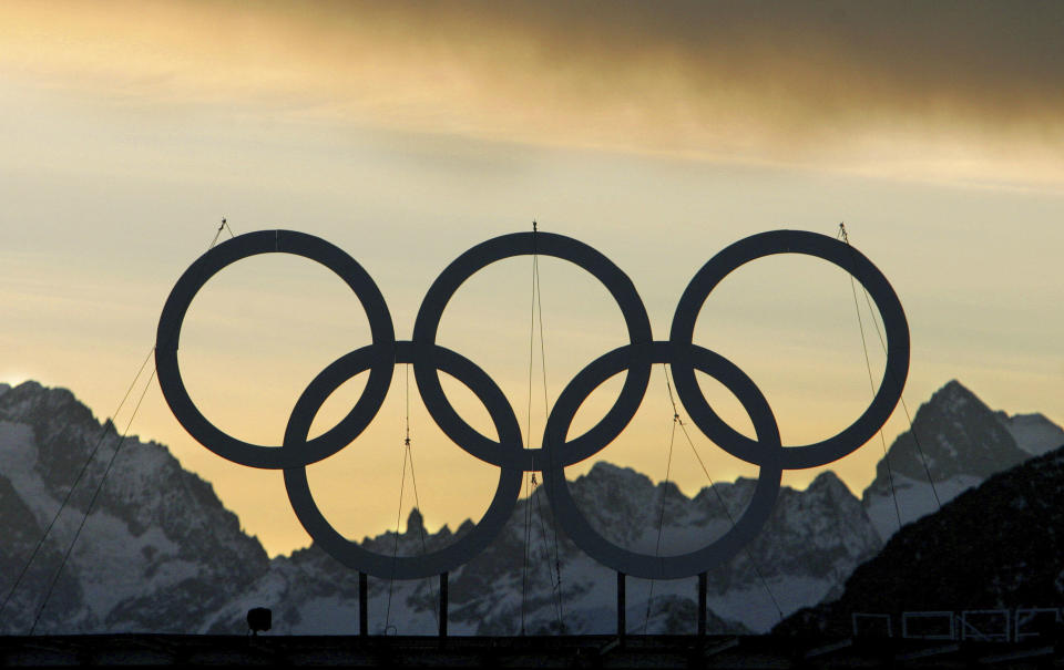 FILE - Large Olympic rings are seen at sunset on the roof of the hotel being used as the athlete's village for the alpine events in the village of Sestriere, northern Italy, Feb. 2, 2006. (AP Photo/Kevin Frayer, File)