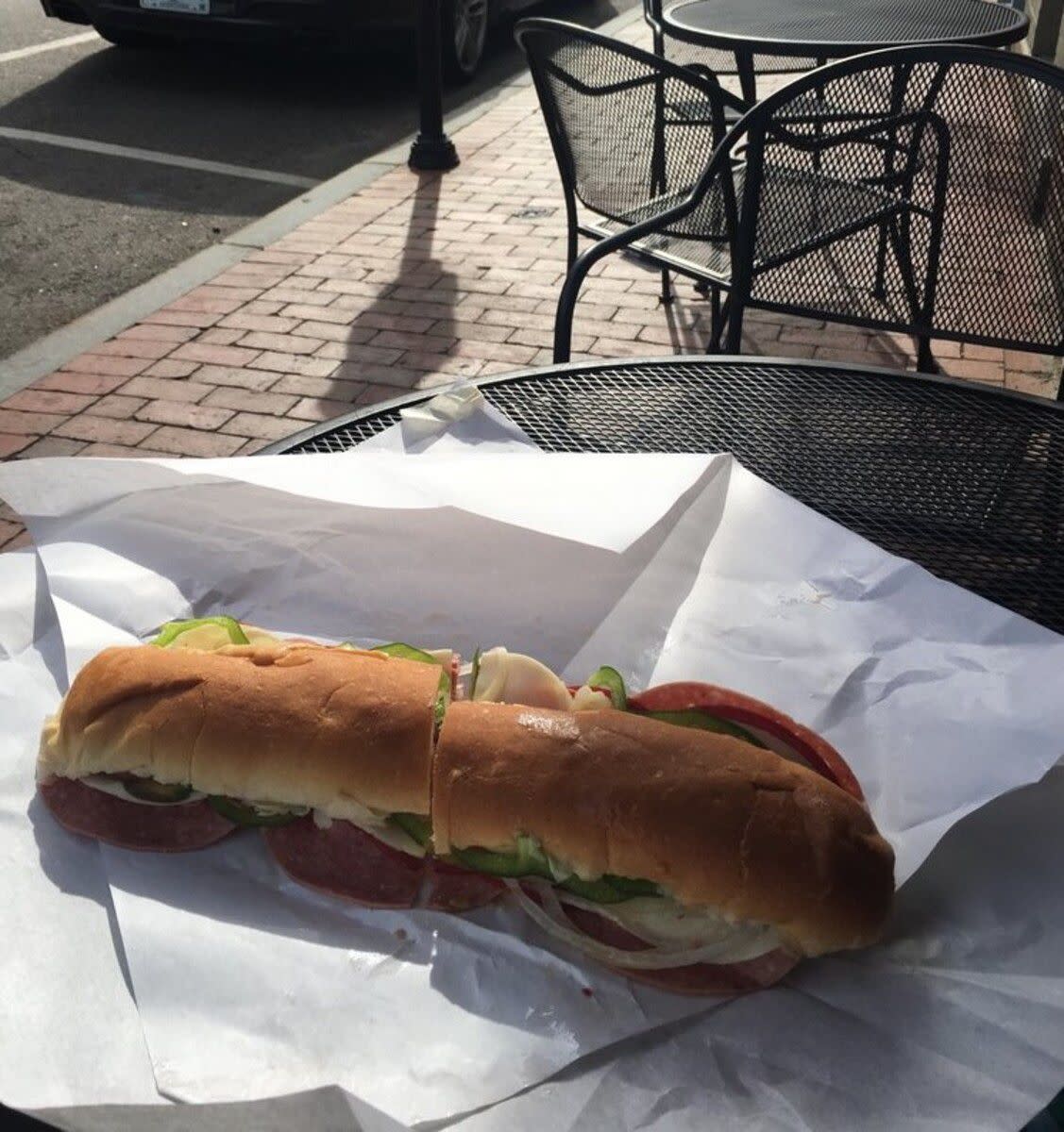 Moe's Original Italian Sandwich on a white serving paper, Moe's Italian Sandwiches, Portsmouth, New Hampshire, on a black wire table in an outside seating area