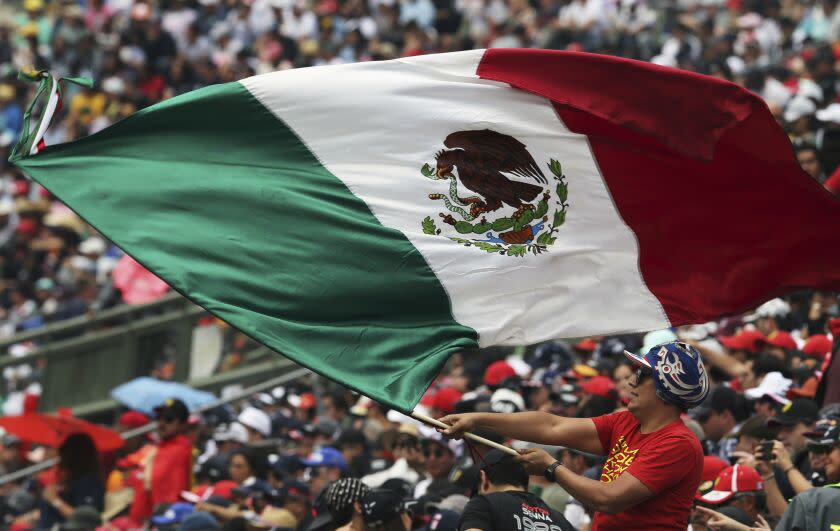 A fan flies a Mexican flag during the qualifying session for the Formula One Mexico Grand Prix auto race at the Hermanos Rodriguez racetrack in Mexico City, Saturday, Oct. 26, 2019. (AP Photo/Marco Ugarte)