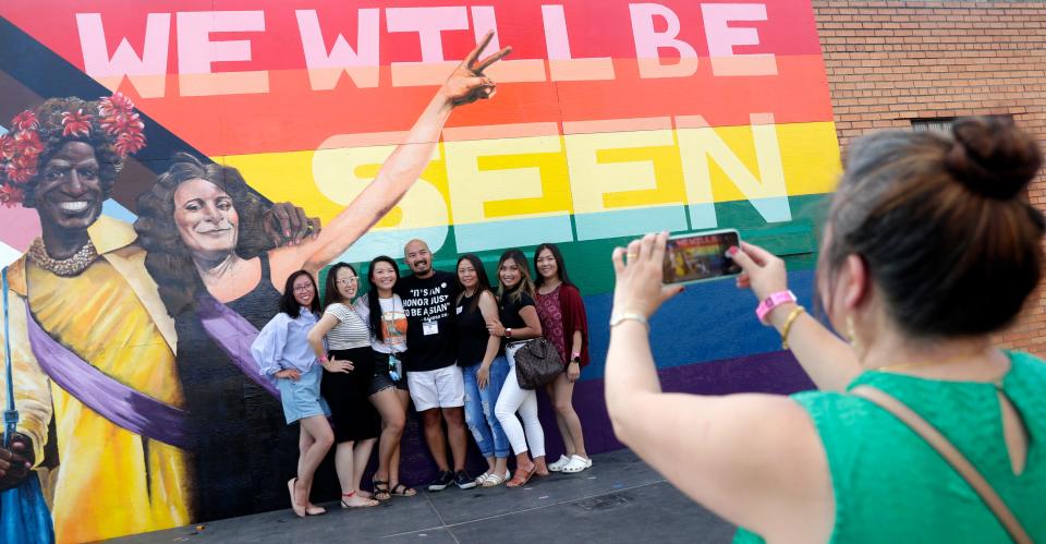 Artist Chue Lo, center, takes photos with family, friends and supporters on Aug. 21, 2021, in front of the LGBTQ+ mural he painted outside Napalese Lounge and Grille in Green Bay, Wis.