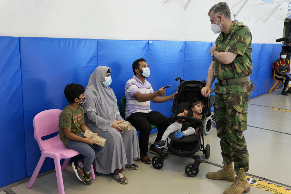 Rear Admiral Henrique Gouveia e Melo gives a Vaccination Task Force patch, like the one he wears on his shoulder, to a family at a vaccination center in Lisbon, Tuesday, Sept. 21, 2021. As Portugal nears its goal of fully vaccinating 85% of the population against COVID-19 in nine months, other countries want to know how it was able to accomplish the feat. A lot of the credit is going to Gouveia e Melo. (AP Photo/Armando Franca)