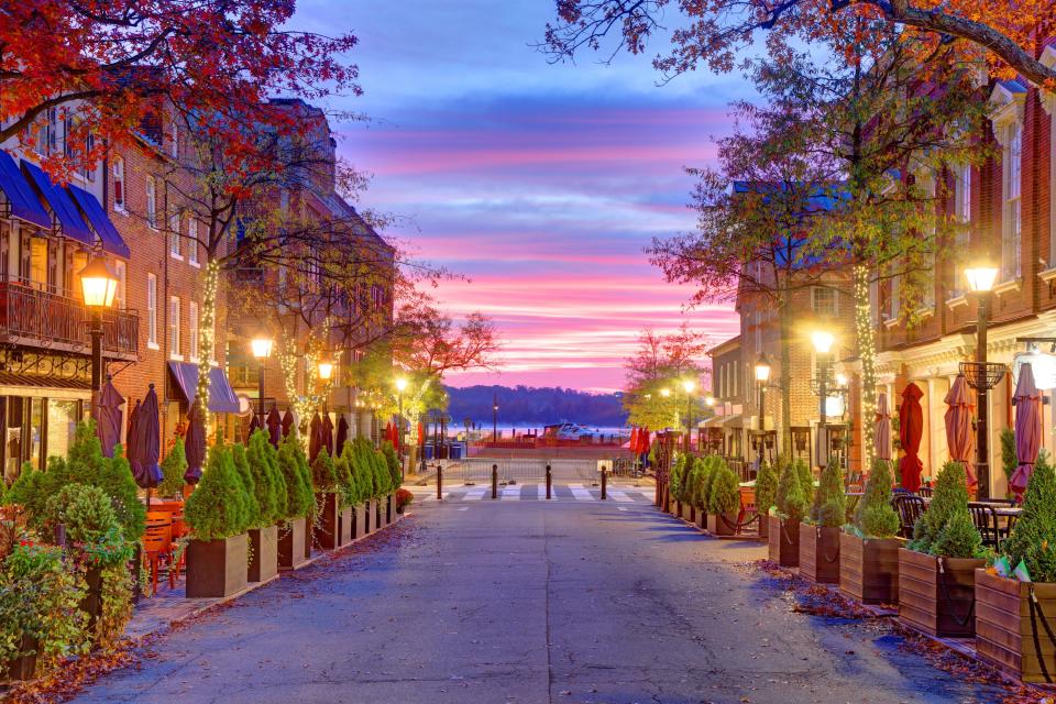 Quaint King Street spans 20 blocks from the Potomac River through Old Town Alexandria, Virginia. Historic buildings line the street including City Hall, which features a clock tower designed by Benjamin Henry Latrobe, known for his work on the US Capitol. One of the city’s four Spite Houses is located at 205 King Street and is just 11 feet, 9 inches wide.