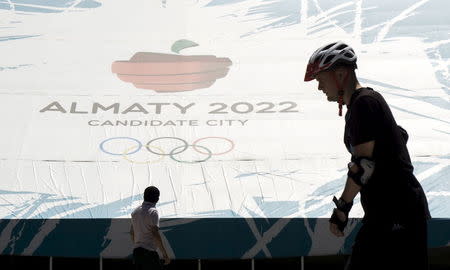 People walk past a banner promoting Almaty for 2022 Winter Olympic Games at the Medeu skating oval in Almaty, Kazakhstan, July 26, 2015. REUTERS/Shamil Zhumatov