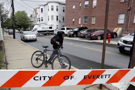 A local youth wheels his bicycle past law enforcement officials are gathered on a residential street in Everett, Massachusetts June 2, 2015 in connection to a man shot dead by law enforcement in Boston after coming at them with a large knife when they tried to question him as part of a terrorism-related investigation, authorities said. REUTERS/Brian Snyder