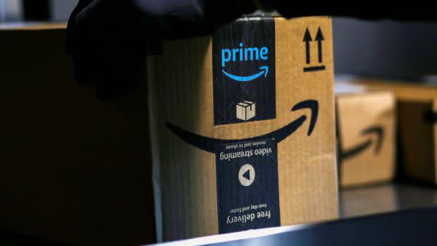 An Amazon worker delivers a package with Prime branding