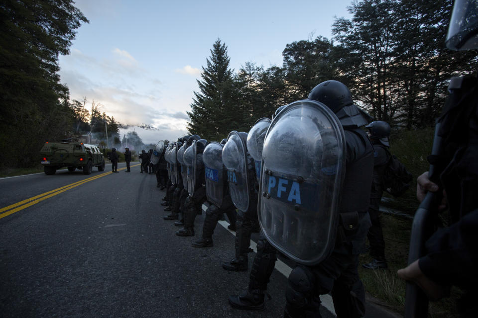 La policía federal se alinea a lo largo de una carretera mientras trabajan para desalojar a los indígenas mapuches de tierras que han ocupado durante años cerca de Villa Mascardi, Argentina, el martes 4 de octubre de 2022. (AP Foto/Matías Garay)