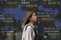 A woman walks by an electronic stock board of a securities firm in Tokyo, Tuesday, Aug. 20, 2019. Asian shares were mostly higher Tuesday after Wall Street rallied on the U.S. decision to give Chinese telecom giant Huawei another 90 days to buy equipment from American suppliers. (AP Photo/Koji Sasahara)