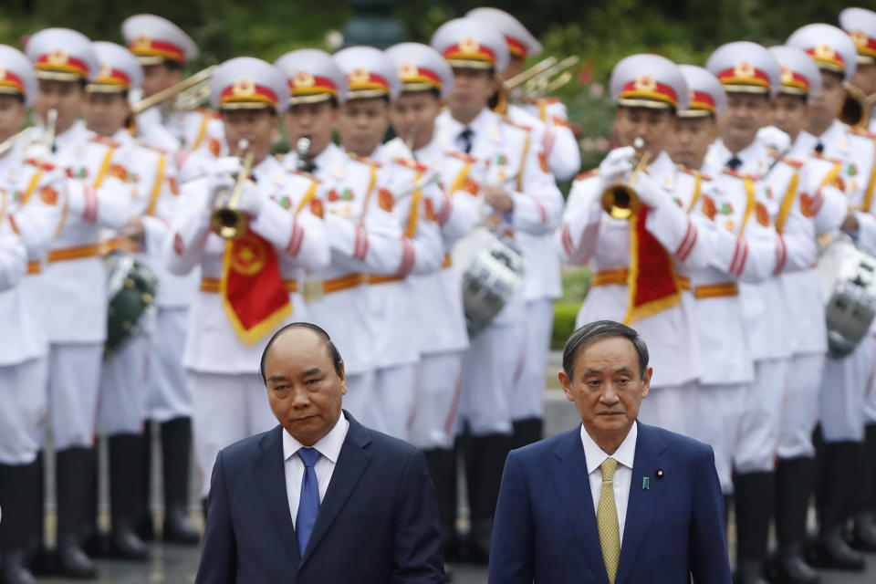 Japanese Prime Minister Yoshihide Suga, right, and his Vietnamese counterpart Nguyen Xuan Phuc, left, attend a welcoming ceremony at the Presidential Palace in Hanoi, Vietnam Monday, Oct. 19, 2020. (Kham/Pool Photo via AP)