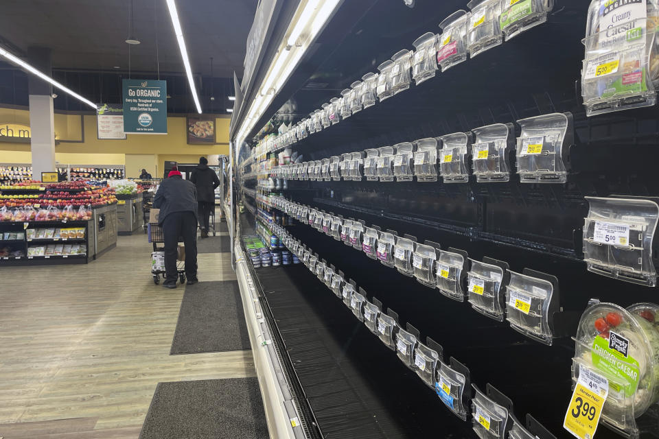 Shoppers walk past empty aisles of produce at a Safeway on Tuesday, Jan. 11, 2022, in Washington. Shortages at U.S. grocery stores have grown in recent weeks as new problems — like the fast-spreading omicron variant and severe weather — have piled on to the supply chain struggles and labor shortages that have plagued retailers since the coronavirus pandemic began. (AP Photo/Parker Purifoy)