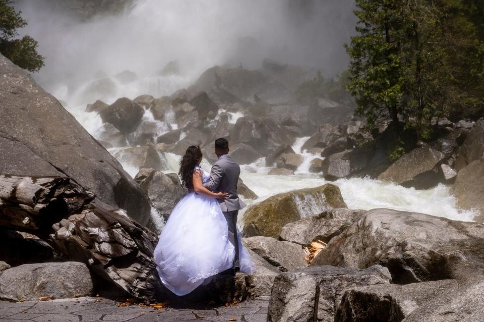 A newly married couple poses for pictures Thursday, May 25, 2023 at the base of Yosemite Falls in Yosemite National Park.