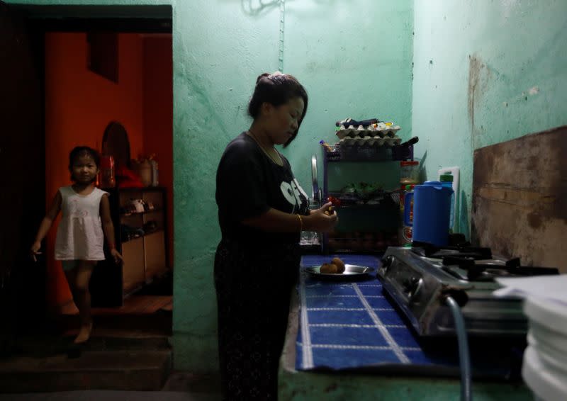 Nepali housewife Shiba Kala Limbu peels potatoes to cook as her five-year-old daughter Masim Limbu enters the room in Kathmandu