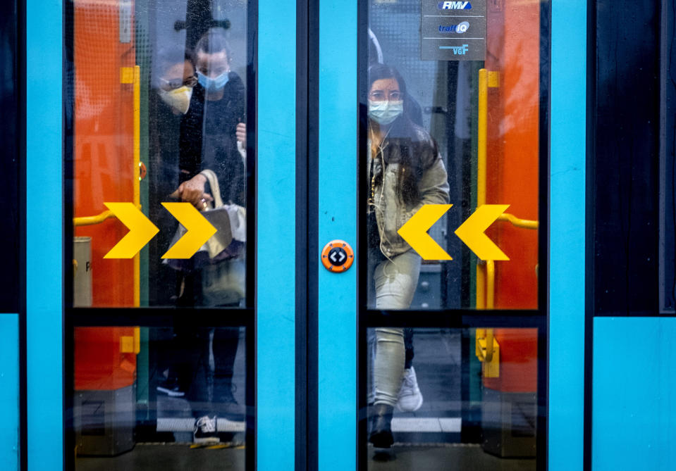 Pasajeros con mascarilla entran el miércoles 28 de octubre de 2020 al metro en Fráncfort, Alemania. (AP Foto/Michael Probst)