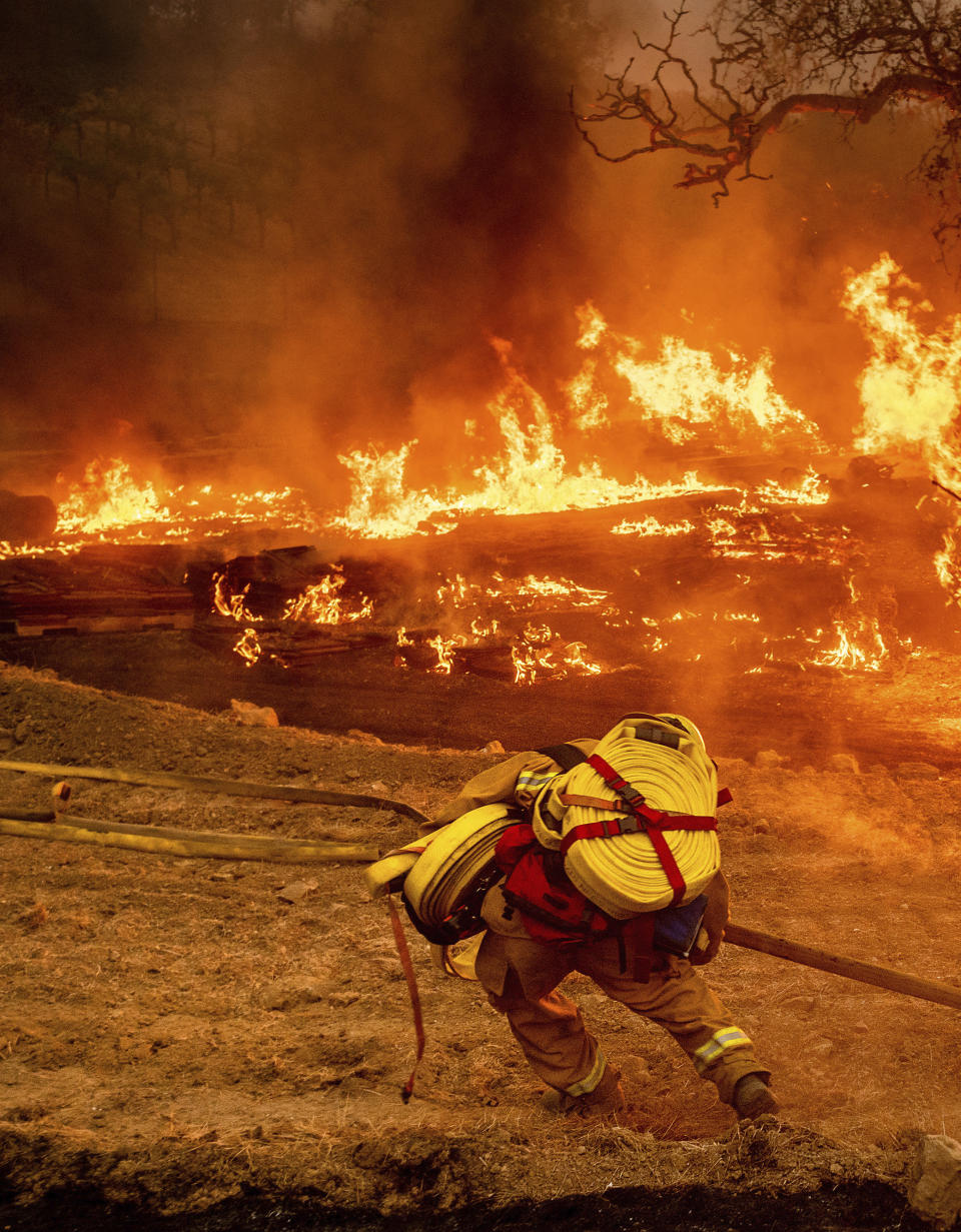 A firefighter carries hose while battling the Glass Fire in a Calistoga, Calif., vineyard Thursday, Oct. 1, 2020. (AP Photo/Noah Berger)