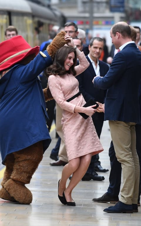 Duchess of Cambridge dances with a person in a Paddington Bear outfit  - Credit: AFP