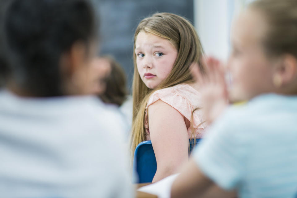 Young girl sitting in class and looking behind her at other classmates