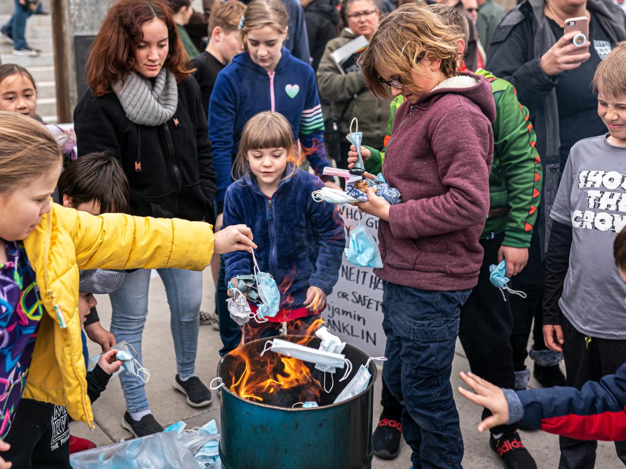 Young attendees toss surgical masks into a fire during a mask burning event at the Idaho Statehouse on March 6, 2021 in Boise, Idaho. (Getty Images)