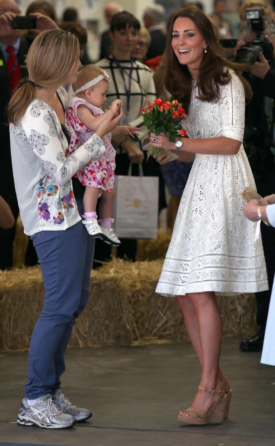 Britain's Kate, the Duchess of Cambridge, smiles after getting flowers from a baby during a tour of the Sydney Easter Show in Sydney, Australia Friday, April 18, 2014. Britain's Prince William and his wife Kate, along with their son Prince George, are on the 10-day official visit. (AP Photo/Rick Rycroft)