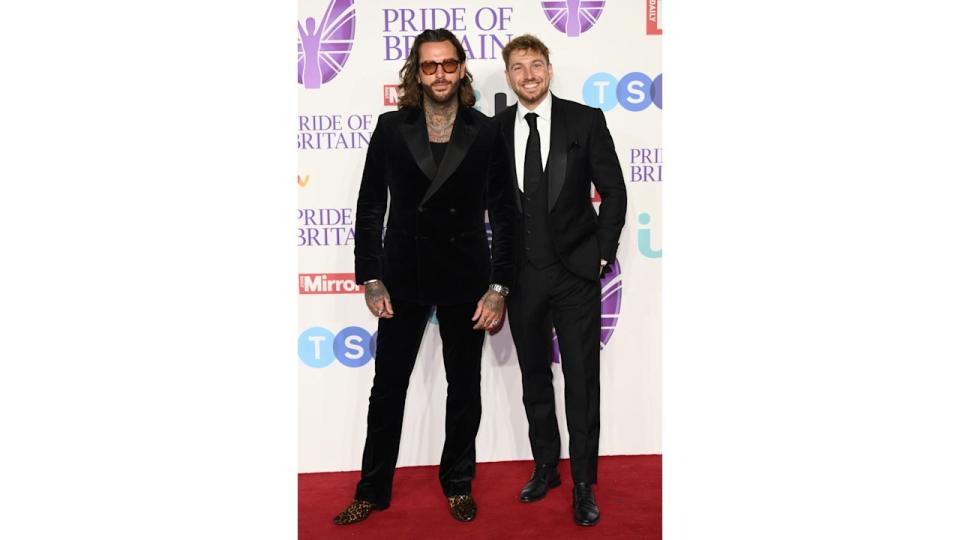 two men on red carpet wearing suits 