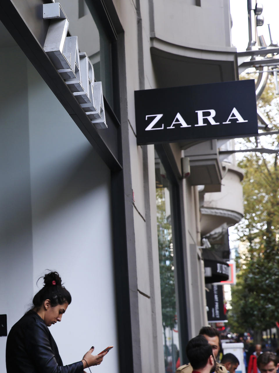 FILE - In this Friday, Nov. 3, 2017 file photo, a shopper exits a branch of fashion retailer Zara in an upscale Istanbul neighborhood. Inditex, the retail giant that owns Zara, H&M and many other brands, announced a sustainability pledge in July, for example, saying it wants all its clothes to be made from sustainable or recycled fabrics by 2025. (AP Photo/Lefteris Pitarakis, File)