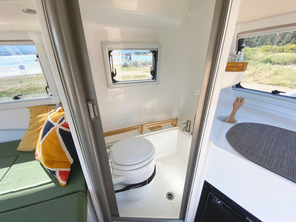 Inside the trailer with a kitchen, bathroom, and couch-like space.