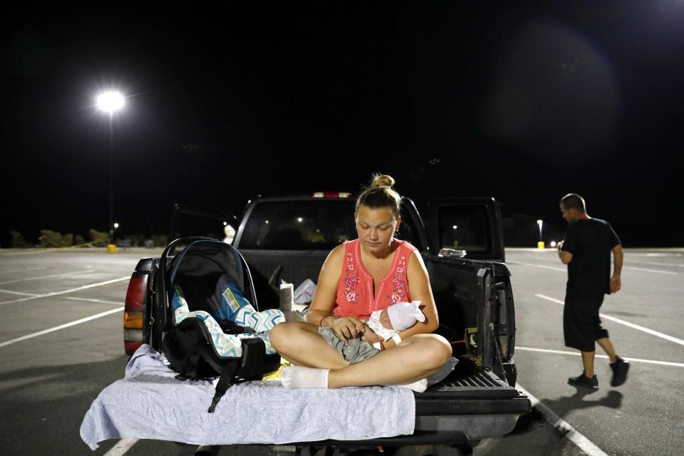 Lorrainda Smith sits with her 2-day-old son, Luke, as she contemplates with her husband, Wilmer Capps, right, sleeping in their truck in a parking lot after their home was damaged from Hurricane Michael and they were told a nearby shelter was closed, in Panama City, Fla., Monday, Oct. 15, 2018. "One day we had it all, the next we had nothing," said Smith. "This is not what I thought I'd be bringing him back to." The family eventually received a police escort to a nearby hospital for assistance as a nightly curfew prohibits the public from being out past dark. (AP Photo/David Goldman)