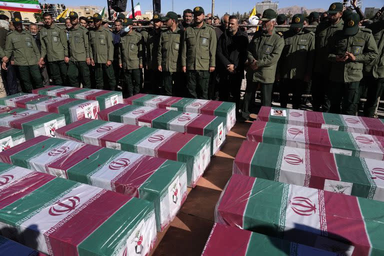 Miembros de la Guardia Revolucionaria de Irán, junto a ataúdes, cubiertos con la bandera nacional, de las víctimas de un doble atentado, durante su funeral, en la ciudad de Kerman, el 5 de enero de 2024. (AP Foto/Vahid Salemi)