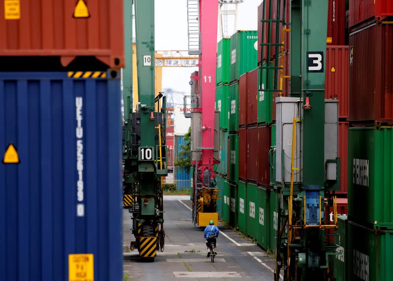 FILE PHOTO: A man on a bicycle rides past containers at an industrial port in Tokyo