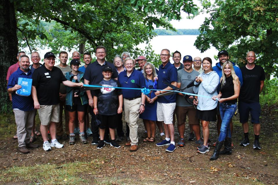 A group of representatives from City Utilities, Ozarks Greenway, TrailSpring, Watershed Committee of the ozarks and more gathers for a ribbon cutting ceremony at Fellows Lake July 30, 2022.