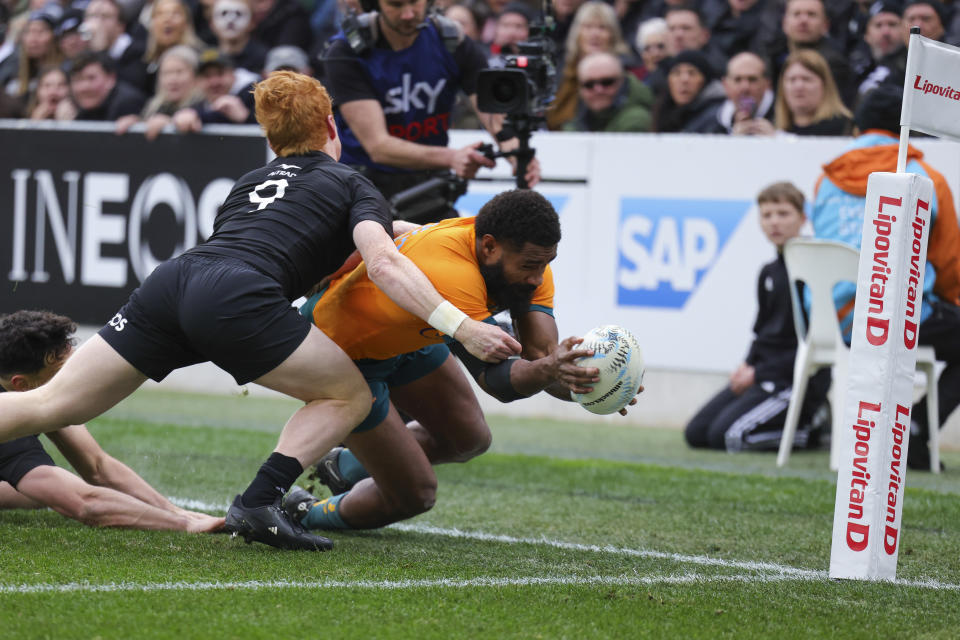 Australia's Marika Koroibete dives over to score a trey in the tackle of New Zealand's Findlay Christie during the Bledisloe Cup rugby test match between the All Blacks and Australia in Dunedin, New Zealand, Saturday, Aug. 5, 2023. (Derek Morrison/Photosport via AP)