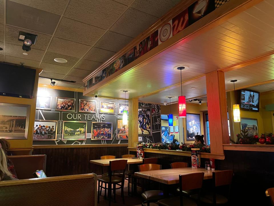 Interior of Applebee's with dim lighting, several empty tables, and signs decorating the wall