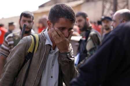 A rebel fighter reacts while walking next to Syrian Army soldiers prior to evacuating the besieged Waer district in the central Syrian city of Homs, after a local agreement reached between rebels and Syria's army, Syria September 22, 2016. REUTERS/Omar Sanadiki